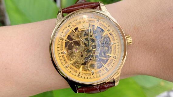 oe50201902-omea-co-nam-day-da-lo-co-8-570x320-1 Đồng hồ nam Omega máy lộ cơ dây da nâu mặt vàng